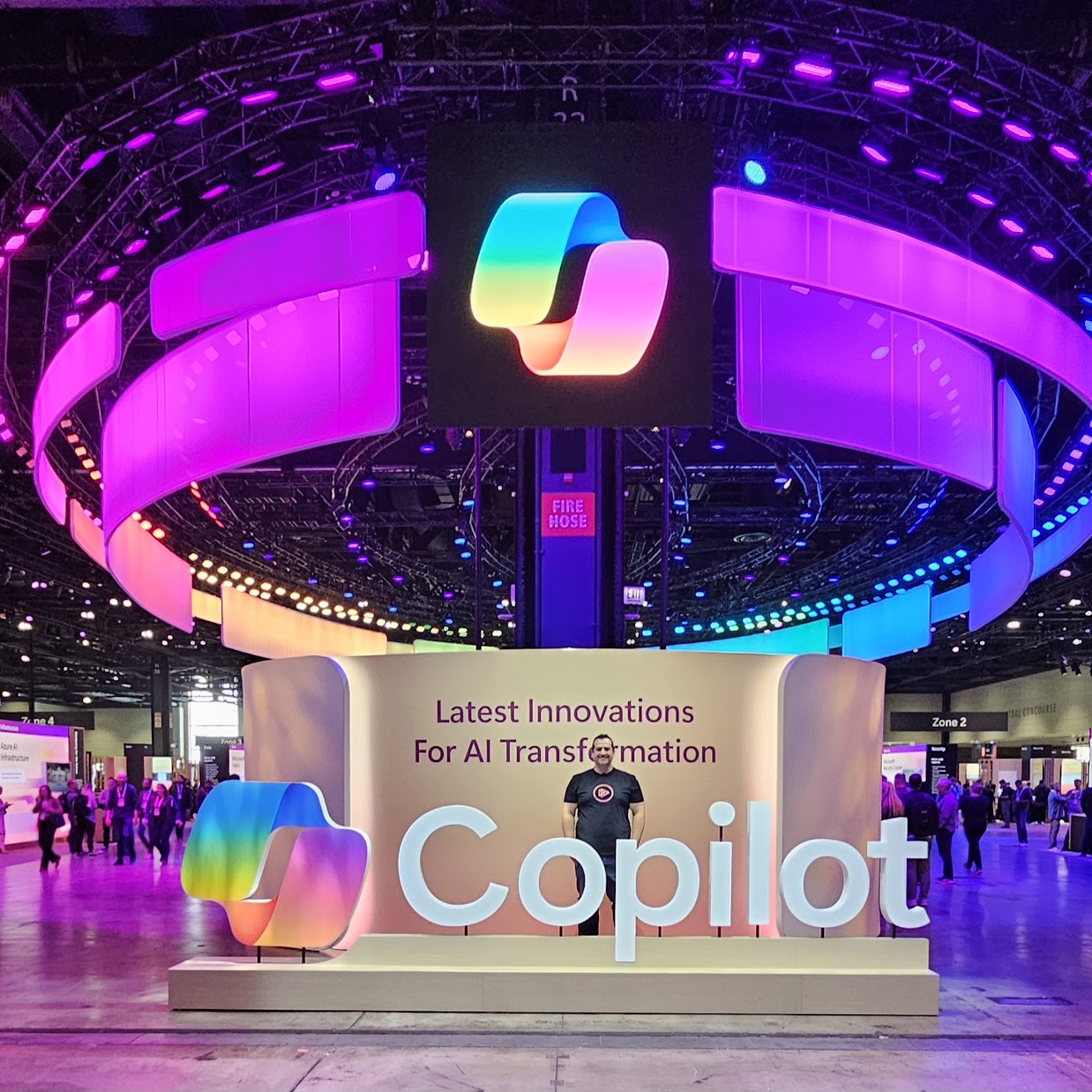 Vlad Catrinescu standing in front of a giant Copilot sign in the Microsoft Ignite 2024 expo hall