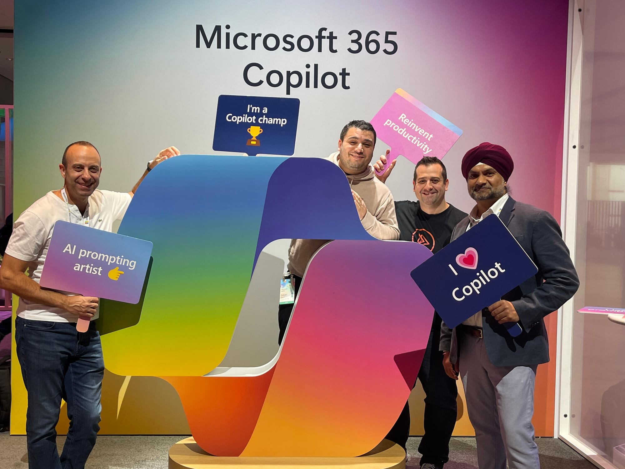 Vlad and three friends holding Copilot champ and I love Copilot signs at the Microsoft 365 Copilot booth at Ignite 2024